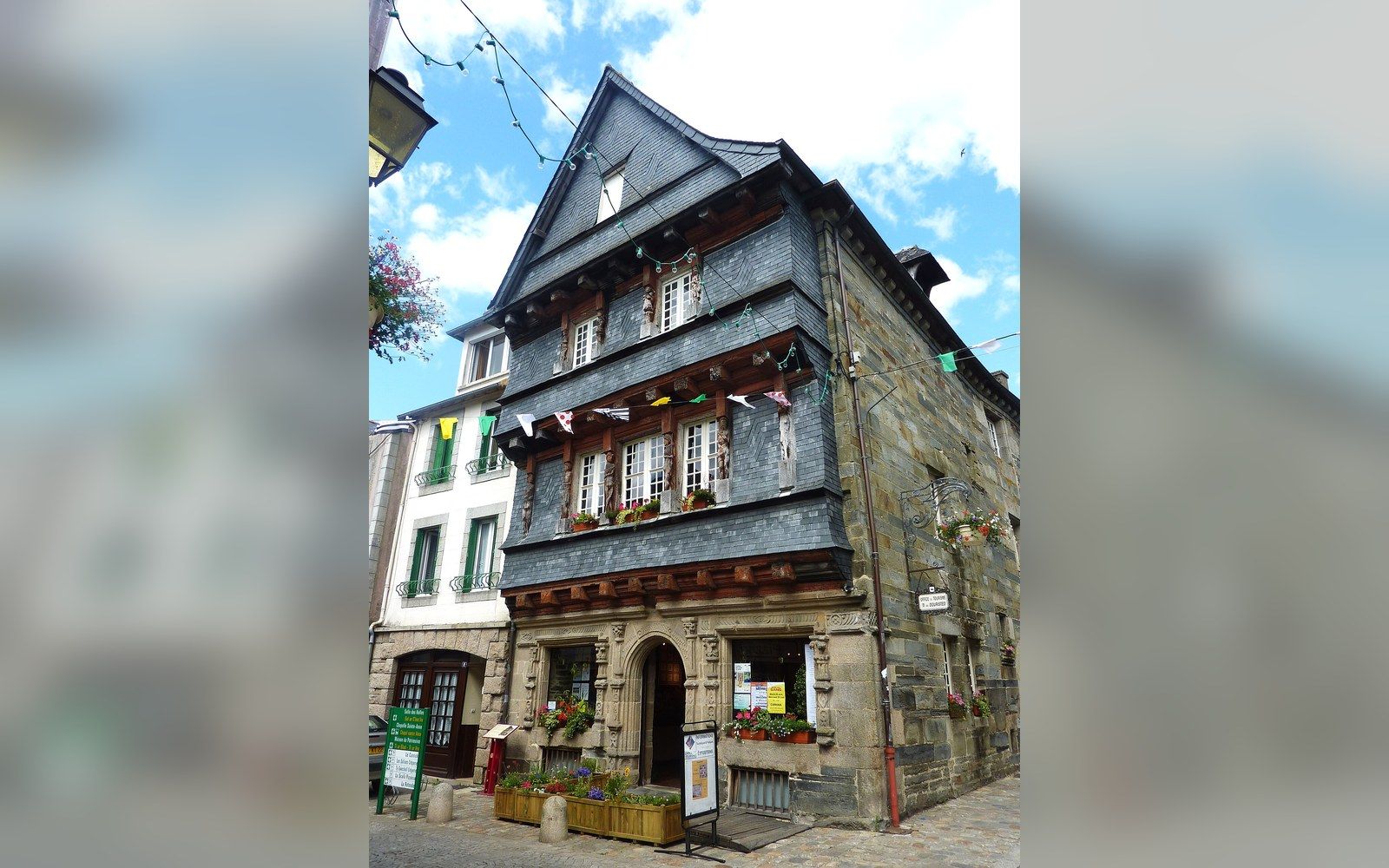 Slate-covered timber-framed corner building with flower boxes and bunting on a street corner